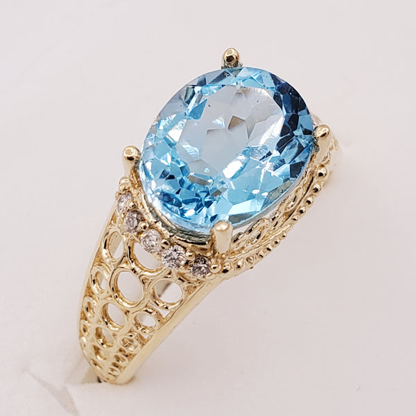 14kt yellow gold ring with one prong set oval cut natural blue topaz and diamonds (0.15cts)